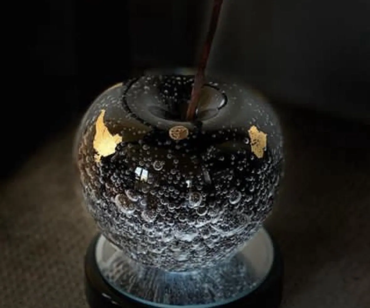 Black Jack, a near-black glass apple with gold leaf and a rusty nail stem