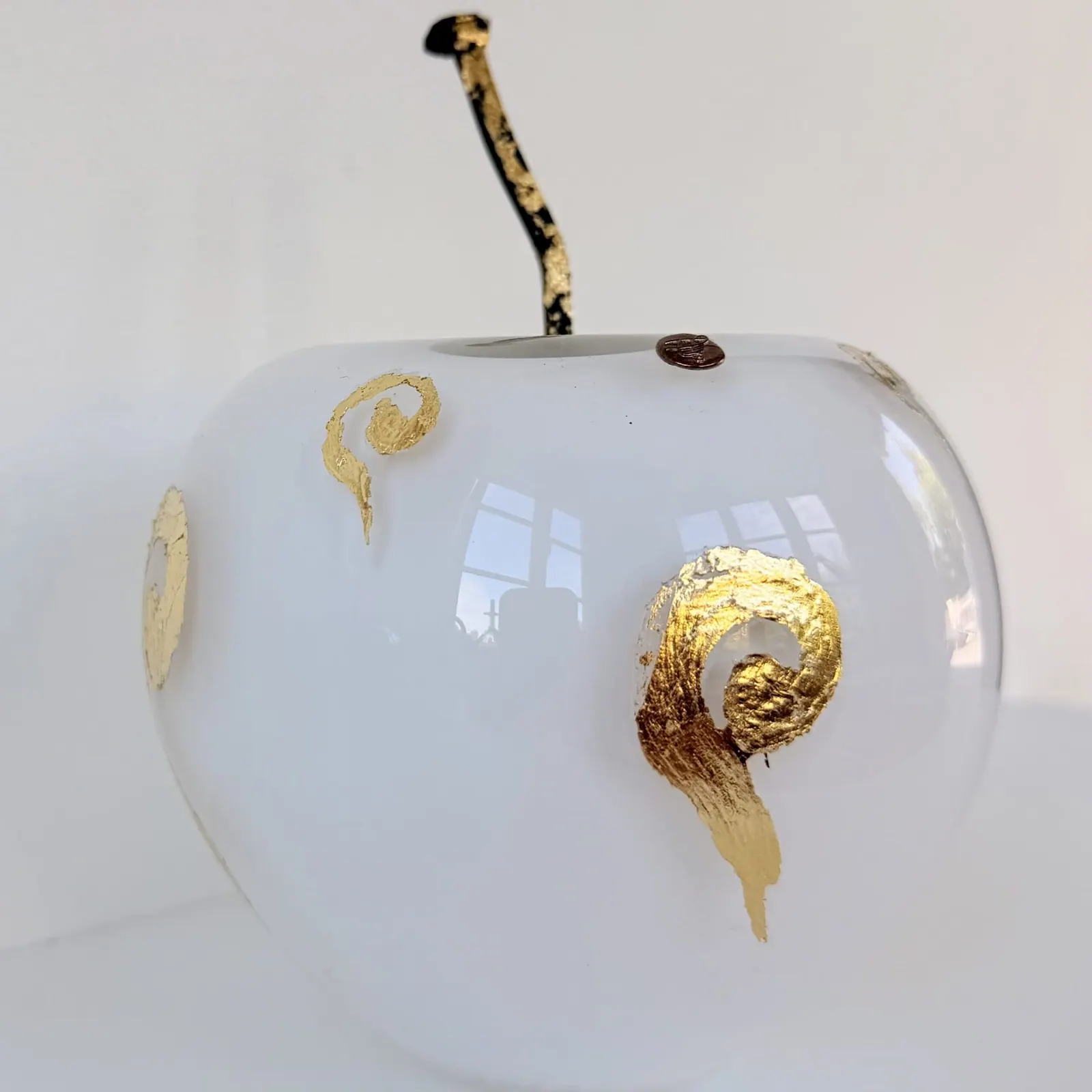 Celestial Whisper, a white glass apple with gold leaf and a rusty nail stem
